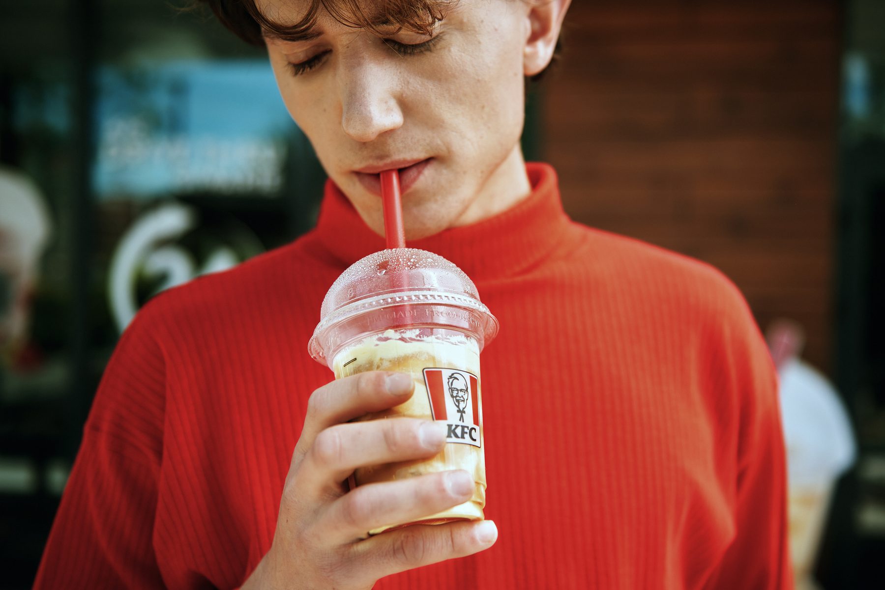 Model w czerwonym golfie z napojem KFC