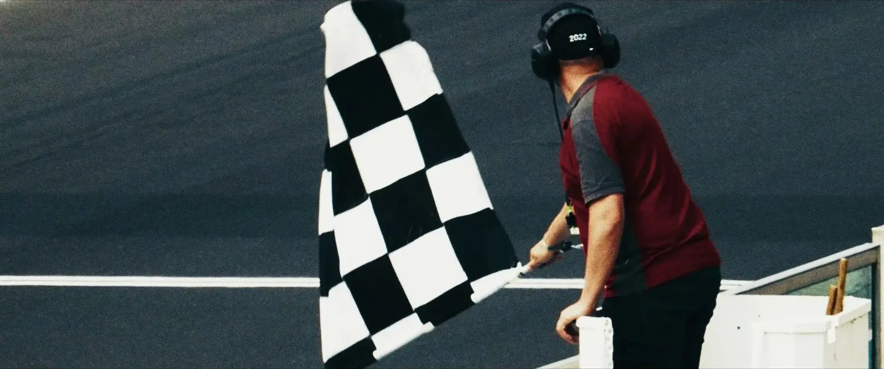 Sędzia z flagą w szachownicę nad torem wyścigowym, kadr z serialu The Community of Speed